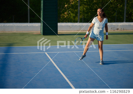 Woman playing tennis on outdoor court in sunny weather Woman playing tennis on outdoor court in sunny weather 116298829