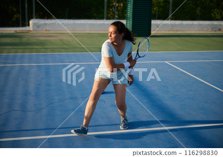 Female tennis player in action on blue outdoor court Female tennis player in action on blue outdoor court 116298830