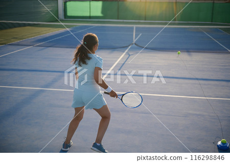 Woman practicing tennis on outdoor court hitting ball 116298846