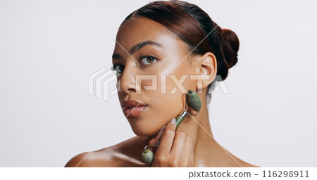 Face roller, glow and woman with skincare, shine and treatment on grey studio background. Portrait, person and model with tool, wellness or mockup space with skincare, dermatology or grooming routine 116298911