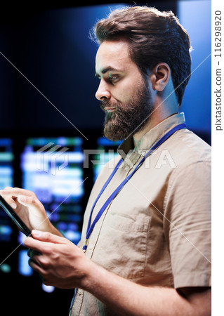Cloud computing business executive imputing audit data in server room supporting AI through high performance computing. Skillful expert making sure supercomputers are operating flawlessly 116298920