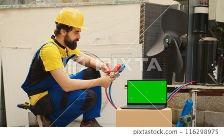 Certified technician hired by home owner to detect cause of damage to air conditioner, checking freon level values measured by professional manifold meters, displayed on chroma key laptop Certified technician hired by home owner to detect cause of damage to air conditioner, checking freon level values measured by professional manifold meters, displayed on chroma key laptop 116298975