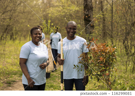 Portrait of a couple volunteering to plant trees and collect garbage from the forest, showing devotion for ecological justice. Environmental volunteers fight nature preservation. Portrait of a couple volunteering to plant trees and collect garbage from the forest, showing devotion for ecological justice. Environmental volunteers fight nature preservation. 116299081
