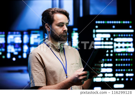 Qualified expert doing annual system review, checking data on tablet of needed server mendings. Clusters housing developed storage infrastructure supporting critical IT workloads 116299128