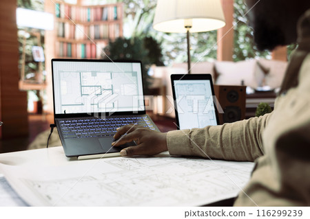 Businessman using digital tools to draft and plan office spaces to relocate, reviewing blueprints for a strategic and professional layout. Entrepreneur searching for new creative workspaces. 116299239