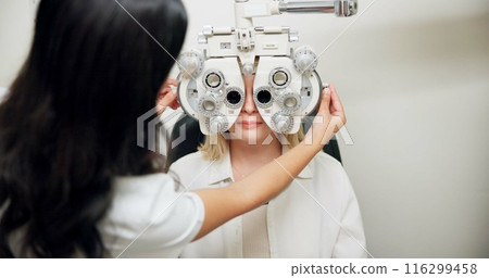 Optometrist, woman and phoropter for eye exam, vision and wellness in consultation room at hospital. People, doctor and patient with machine, lens and assessment for healthy eyesight in clinic Optometrist, woman and phoropter for eye exam, vision and wellness in consultation room at hospital. People, doctor and patient with machine, lens and assessment for healthy eyesight in clinic 116299458