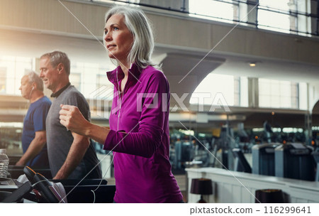Woman, running on treadmill and training by music in gym club, breathing and cardio for fitness in wellness. Mature, female athlete or podcast for exercise, person and workout by speed machine 116299641