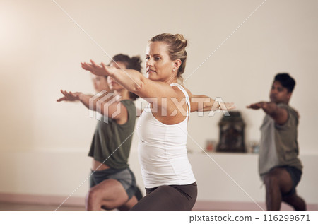 Woman, warrior pose and instructor in yoga class, balance and exercise together for peace in studio. Female person, pilates and coach training a group of people, stretching and yogi for wellness Woman, warrior pose and instructor in yoga class, balance and exercise together for peace in studio. Female person, pilates and coach training a group of people, stretching and yogi for wellness 116299671