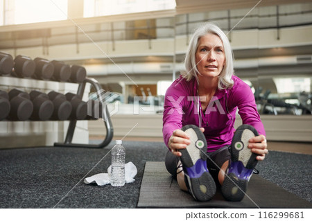 Mature woman, warm up and legs on gym floor, stretching and challenge for progress in workout. Person, muscle and start training for wellness with development, ready and exercise mat at fitness club 116299681
