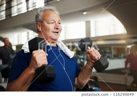 Mature, happy man and weightlifting with dumbbells for fitness, workout or indoor exercise at gym. Male person with smile or earphones for strength training, muscle gain or music at health club 116299849