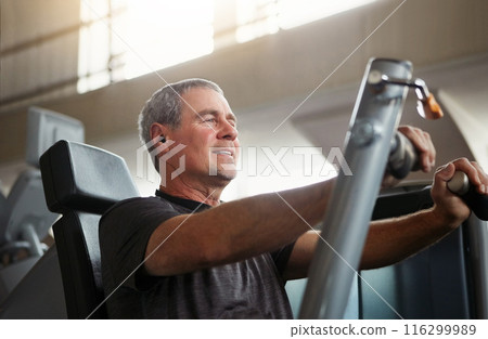 Mature, happy man and chest press with machine for workout, fitness or indoor exercise at gym. Active male person with earphones on equipment for strength, muscle gain or training at health club 116299989