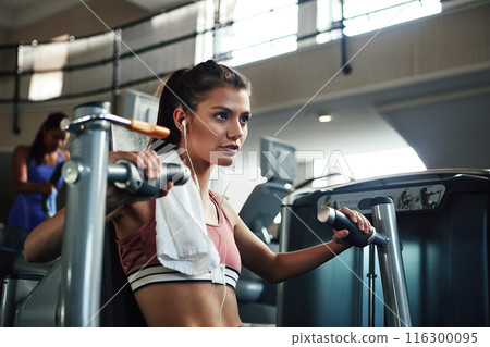 Girl, workout and chest press in gym for fitness, power and muscle development with earphones or towel. Athlete, machine and exercise in sports club for wellness, health and training with resilience 116300095