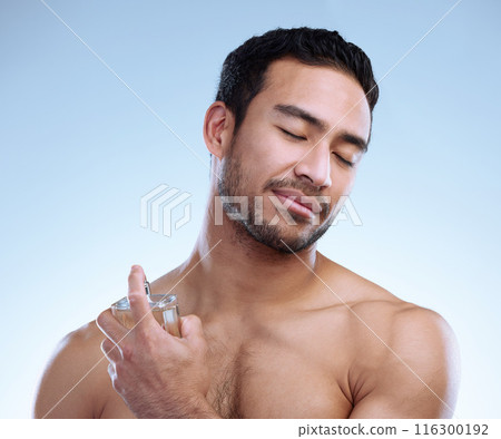 Man, perfume and spray in studio for wellness, hygiene and calm for self care with zen and smile. Deodorant, scent and male person by white background for cologne, cosmetics and skincare routine 116300192