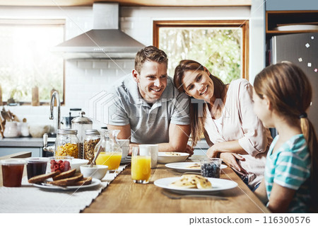 Family, food and kid with parents in morning for healthy breakfast, diet and child development. Happy, mother and father with little girl on weekend for nutrition, growth support and care at home 116300576