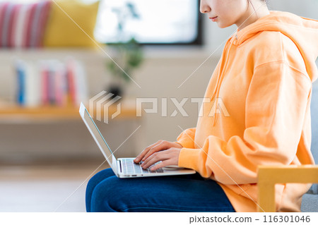 A young woman using a laptop in her living room. A young woman using a laptop in her living room. 116301046