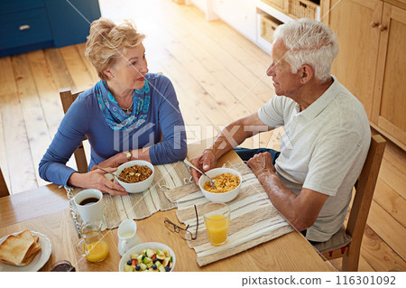 Elderly, couple or talking with eating at breakfast in dining room for nutrition, healthy meal or retirement. Senior, people or porridge in home with conversation, relax or morning routine from above 116301092