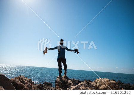 Woman photographer enjoy the view on sunrise seaside rocks 116301293
