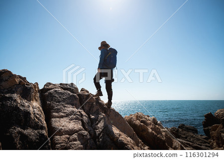 Woman photographer enjoy the view on sunrise seaside rocks Woman photographer enjoy the view on sunrise seaside rocks 116301294