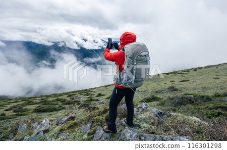 Hiking woman use smart phone taking photo on high altitude mountains Hiking woman use smart phone taking photo on high altitude mountains 116301298