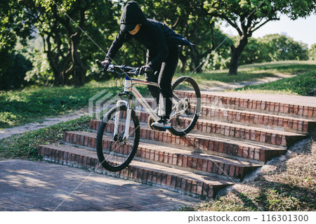 Woman free rider riding bike going down city stairs 116301300