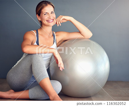Ball, fitness and portrait of woman on floor in studio with gray background for workout. Exercise, health or smile and happy person with equipment for physical improvement, training or wellness 116302052