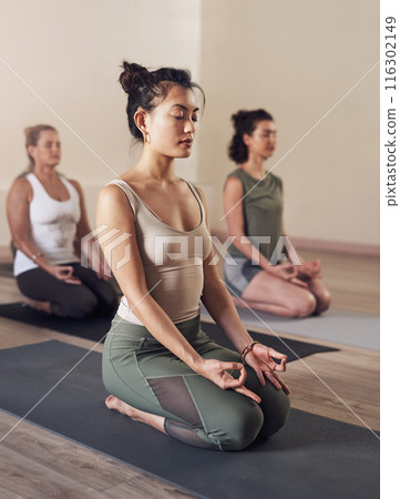Woman, lotus and meditation in yoga class with group for spiritual wellness, relax and zen on floor mat. Yogi, people and concentration in health studio for holistic workout, body balance and fitness Woman, lotus and meditation in yoga class with group for spiritual wellness, relax and zen on floor mat. Yogi, people and concentration in health studio for holistic workout, body balance and fitness 116302149