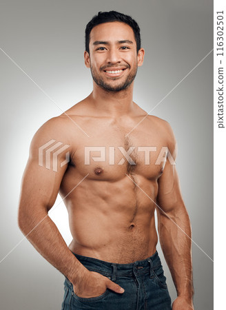 Man, portrait and happy in studio with abs or muscles, shirtless and grey background with model or bodybuilder. Jeans, strong chest and Asian male person on backdrop, confidence with six pack 116302501
