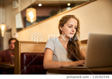 Woman, serious and research at coffee shop with laptop as university student for elearning or online education. Female learner, studying and revision in distance leaning for college exams and project 116302548