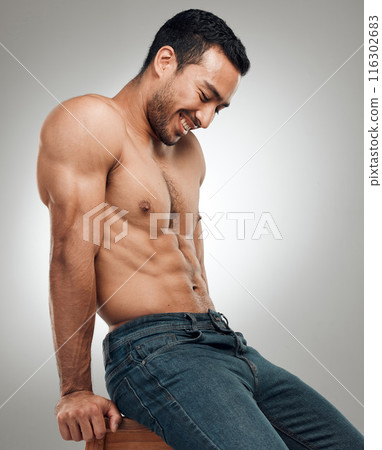 Man, chair and topless in studio for fitness, wellness and strong abs muscle on gray background. Male person, denim jeans and shirtless for health, bodybuilder and proud of body or workout results 116302683