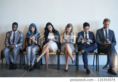 Technology, business people and group in waiting room for recruitment, interview or hr opportunity. Diversity, employees and row in office for hiring, human resources or corporate job search together 116303074