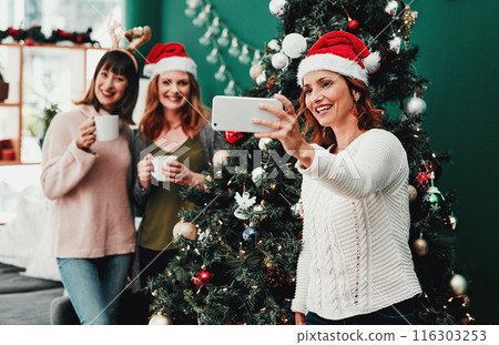 Woman, selfie and Christmas in living room with friends for holiday, celebration and together with coffee. Technology, social media and group in apartment for relax, vacation and hot drink in lounge Woman, selfie and Christmas in living room with friends for holiday, celebration and together with coffee. Technology, social media and group in apartment for relax, vacation and hot drink in lounge 116303253