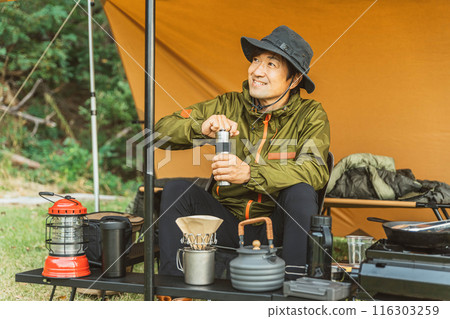 Male camper grinding beans using a coffee mill at camp 116303259