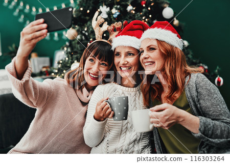 Christmas, selfie and women in apartment with smile, holiday and celebration together with coffee. Technology, friends and group in home or living room for relax, vacation and drink with smile Christmas, selfie and women in apartment with smile, holiday and celebration together with coffee. Technology, friends and group in home or living room for relax, vacation and drink with smile 116303264