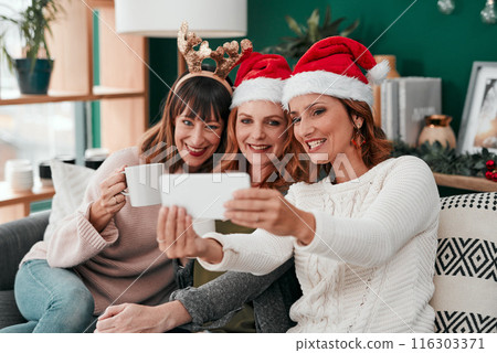 Women, selfie and Christmas on couch in home for holiday, celebration and happiness with coffee. Technology, friends and group in apartment on sofa for relax, vacation and drink in lounge with smile Women, selfie and Christmas on couch in home for holiday, celebration and happiness with coffee. Technology, friends and group in apartment on sofa for relax, vacation and drink in lounge with smile 116303371