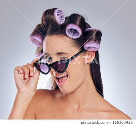 Woman, portrait and sunglasses in hair roller set, hairstyle by white background and happy. Face, model haircare and curlers for cosmetics, beauty salon treatment and makeup with wink in studio 116303426