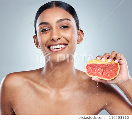 Indian woman, grapefruit and skincare for organic beauty, hand and fruit on gray background. Citrus, food or vitamin c with liquid for hydrated skin or body care, studio or portrait of female person 116303510