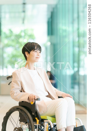 Woman in wheelchair working in office 116304268
