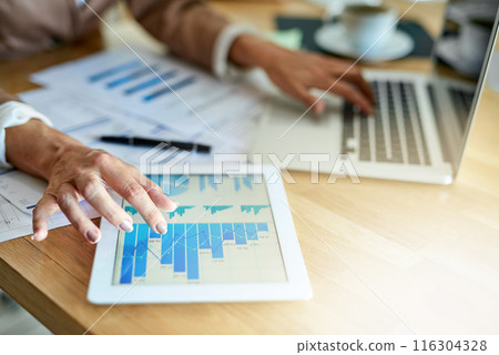 Hands, screen and businessperson with graphs on tablet at desk for data, charts or digital statistics in office. Lens flare. laptop and employee for kpi update, economy growth or review documents 116304328