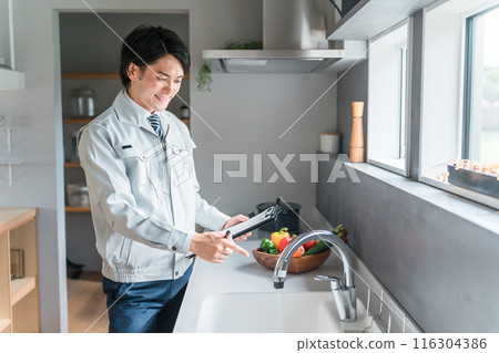 A businessman in work clothes from a plumber, equipment company, remodeler, or construction company checking the water supply A businessman in work clothes from a plumber, equipment company, remodeler, or construction company checking the water supply 116304386