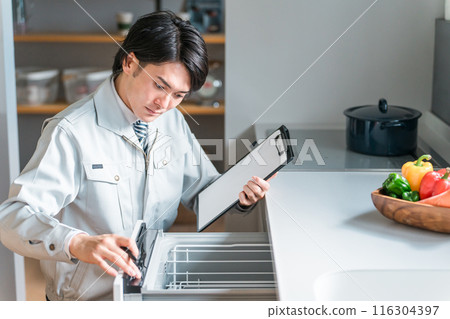 A male businessman in work clothes diagnoses, checks, and assesses the dishwasher and dishwasher in the kitchen. 116304397