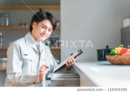 A male businessman in work clothes diagnoses, checks, and assesses the dishwasher and dishwasher in the kitchen. 116304398