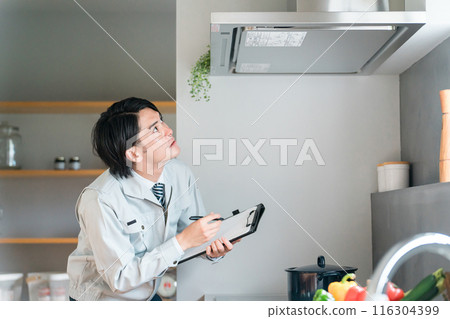 一位穿著工作服的男商人檢查廚房的抽油煙機和換氣扇。 一位穿著工作服的男商人檢查廚房的抽油煙機和換氣扇。 116304399