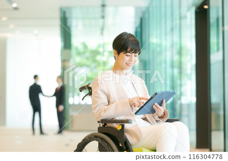 Woman in wheelchair working in office 116304778
