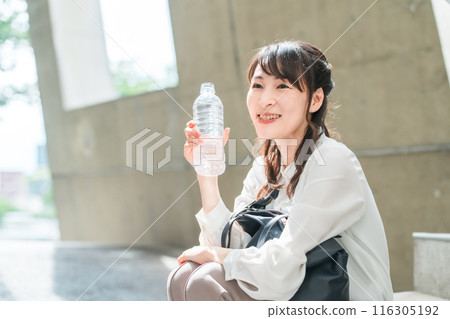 Business woman sitting on the stairs with a plastic bottle (hydration, rest, mineral water) 116305192