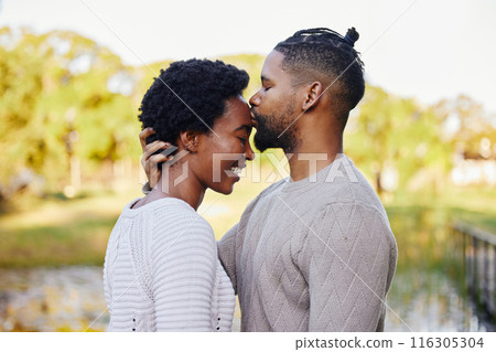 Black couple, happy and forehead kiss by lake for love in park with smile, trees and nature on summer holiday. Man, woman and support or trust outdoor with sunshine, date and vacation in morning Black couple, happy and forehead kiss by lake for love in park with smile, trees and nature on summer holiday. Man, woman and support or trust outdoor with sunshine, date and vacation in morning 116305304