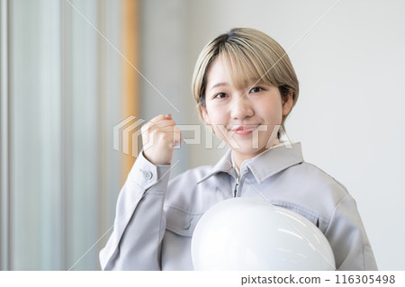 A young woman with short blonde hair wearing work clothes and holding a helmet (fist pump, free hair color, work in your own way) A young woman with short blonde hair wearing work clothes and holding a helmet (fist pump, free hair color, work in your own way) 116305498