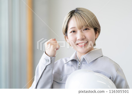 A young woman with short blonde hair wearing work clothes and holding a helmet (fist pump, free hair color, work in your own way) A young woman with short blonde hair wearing work clothes and holding a helmet (fist pump, free hair color, work in your own way) 116305501