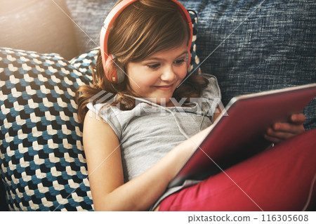 Tablet, headphones and relax with child on sofa in home living room for fun, learning on app or having fun. Toddler, technology and happy girl on couch, streaming movie or typing on social media Tablet, headphones and relax with child on sofa in home living room for fun, learning on app or having fun. Toddler, technology and happy girl on couch, streaming movie or typing on social media 116305608