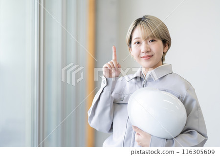 A young woman with short blonde hair wearing work clothes and holding a helmet (pointing, free hair color, working in your own way, work environment) A young woman with short blonde hair wearing work clothes and holding a helmet (pointing, free hair color, working in your own way, work environment) 116305609