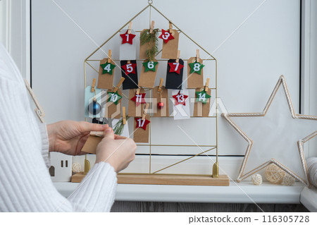 Number on craft paper notes with tasks before Christmas holidays. Female making kraft paper for handmade advent calendar Made with your own hands step by step DIY Number on craft paper notes with tasks before Christmas holidays. Female making kraft paper for handmade advent calendar Made with your own hands step by step DIY 116305728